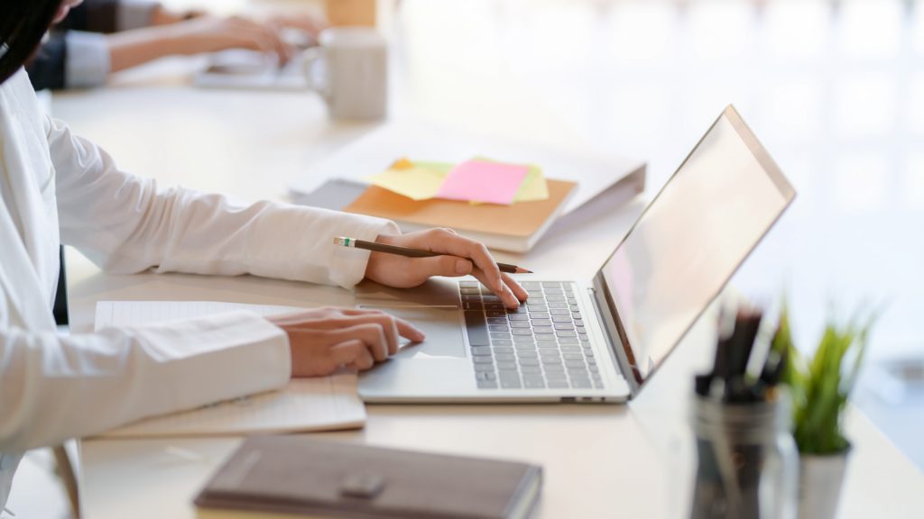 Side view of professional businessman typing laptop and office supplies